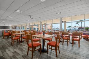 圣徒皮特海滩海豚滩度假酒店的餐厅设有木桌、椅子和窗户。