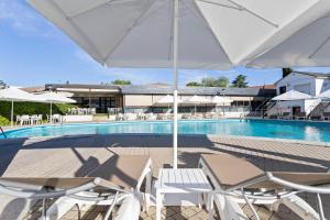 马德里Hotel Best Osuna的一个带白色椅子和遮阳伞的游泳池