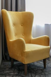 卢布林地区托马舒夫B&B HOTEL Tomaszów Lubelski的坐在房间里一张黄色的皮椅