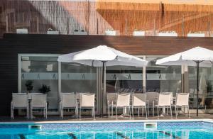 罗列特海岸ALEGRIA Mariner的一座带椅子和遮阳伞的游泳池位于一座建筑旁边