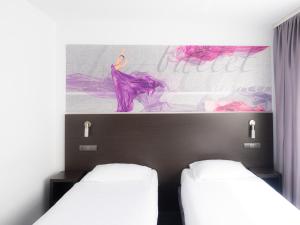 比托姆B&B HOTEL Bytom的墙上画画的房间里设有两张床