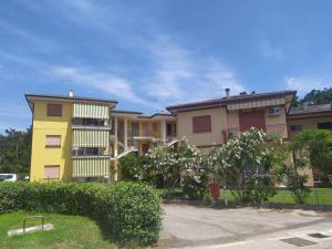 罗索利纳马雷Apartment Rosolina Mare 5的前面有灌木丛的黄色公寓楼