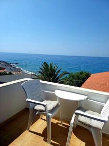 阿吉亚努美利Agia Roumeli Hotel的阳台上配有两把椅子和一张桌子,享有海景