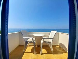 阿吉亚努美利Agia Roumeli Hotel的阳台配有一张桌子和两把椅子,享有海景