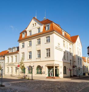 格赖夫斯瓦尔德科隆普林兹酒店的一条城市街道上的白色大建筑