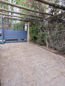 卢汉德库约Rincón Verde Chacras de Coria的石头庭院设有蓝色的围栏和树木