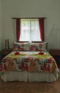 安加罗阿Hostal y Cabañas Aorangi的一间卧室配有一张带红色窗帘的床和窗户
