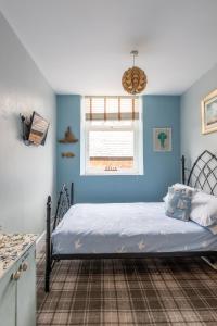 莱瑟姆-圣安妮Beach Snug的一间卧室配有一张蓝色墙壁的床和一扇窗户