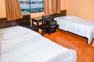 阿亚库乔Hotel Santa Ana的一间卧室设有两张床、一张桌子和一个窗口