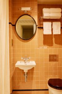 伦敦Grand Hotel Bellevue London的一间带水槽、镜子和卫生间的浴室