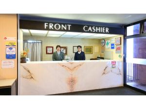 饭山市Hotel Silk in Madarao - Vacation STAY 79656v的两个男人站在前方出纳员的前柜台