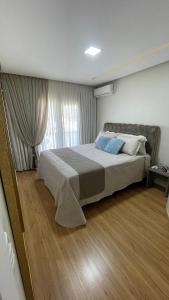 布卢梅瑙Apto climatizado 3 quartos a 3,7km da Vila Germânica的卧室在窗户前配有一张大床