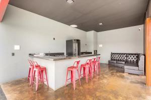 皮雷诺波利斯Requinte, conforto e privacidade的厨房设有酒吧,配有4张红色凳子