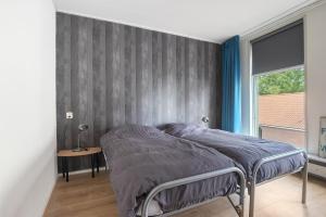 MarssumAppartement De Boppeslach的一间卧室配有一张带灰色墙壁的床
