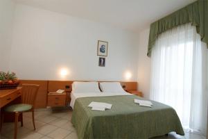 圣乔瓦尼·罗通多Hotel San Francesco的一间卧室配有一张带绿毯的床和一张书桌
