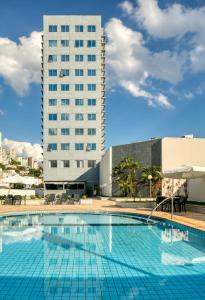 贝洛奥里藏特萨法斯美居BH酒店的一座大型游泳池,其背后是一座高大的建筑