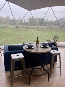 MarmoraOpen Sky Glamping Kawartha Dome的一张桌子、一瓶葡萄酒和帐篷
