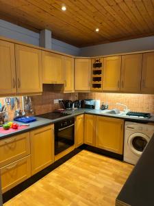蒂珀雷里Cosy home in a beautiful valley的厨房配有木制橱柜、水槽和洗碗机。