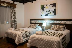 MachachiChuquiragua Lodge & Spa的一间卧室设有两张床,墙上挂着一幅画
