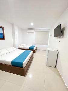 GairaHotel AguaMarina Rodadero Santa Marta的一间带两张床的卧室和一台电视