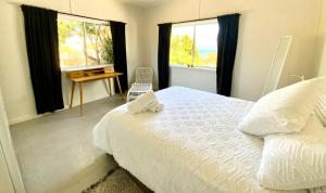 伊登Central Beach house on Chandos的卧室配有一张床、一张书桌和窗户。