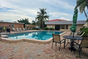 迈尔斯堡Rodeway Inn Fort Myers Central的游泳池旁设有椅子和桌子