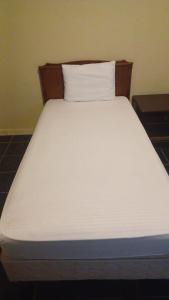 阿可贺巴كريستال الشرقية的一张带木制床头板和白色枕头的白色床