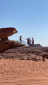 瓦迪拉姆Yellow Star Camp Wadi Rum的一群人在海滩上的岩石上行走