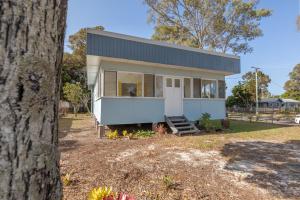 邦加里Entire Beach House on Bribie Island的一座小白色房子,有一棵树