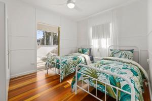 邦加里Entire Beach House on Bribie Island的白色客房的两张床,铺有木地板