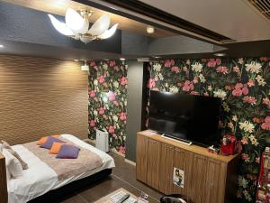 Minatomachiホテルアシュエル的卧室配有平面电视和花卉壁纸。