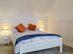 波特帕特里克Anchor Cottage的一张带两个橙色枕头的白色床