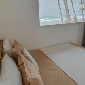 阿杭格默Mermaid Beach的一张带枕头的床和一扇带海滩的窗户