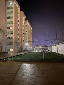 伊瓦格Apartamento completo的夜间在一些建筑前的网球场