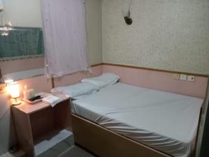 香港嘉湖旅館的小房间设有两张床和一张带台灯的桌子