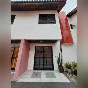 马蒂尼奥斯Triplex White em Caiobá-Matinhos-Pr a 200 mt do mar的黑门和仙人掌的白色房子