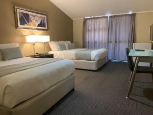奥克兰机场入口酒店的酒店客房设有两张床和一张桌子。