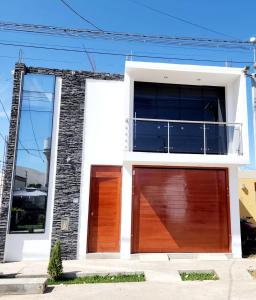 伊察Departamento familiar en Huacachina的白色的房子,设有2扇木制车库门