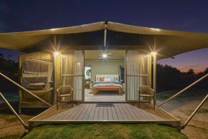 BroadwaterWillow Wood Glamping Retreat的帐篷,甲板上配有一张床和两把椅子