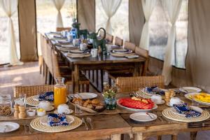 塞伦盖蒂Olmara Camp的一张长木桌子,上面放着食物盘