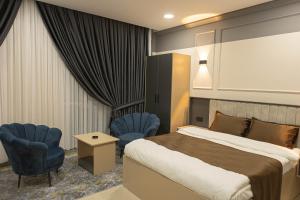 ÇekmeCity Night Suites & Hotels的酒店客房,配有一张床和两张蓝色椅子