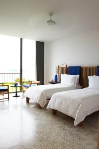 班巴克洛COMO Point Yamu, Phuket- SHA Extra Plus的酒店客房设有两张床和大窗户。
