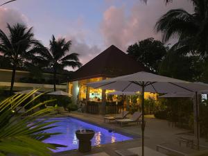 拉威海滩Lotus Bleu Resort & Restaurant的房屋前的带遮阳伞的游泳池