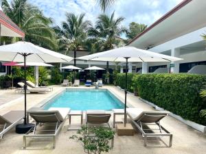 拉威海滩Lotus Bleu Resort & Restaurant的一座带椅子和遮阳伞的游泳池位于一座建筑旁边