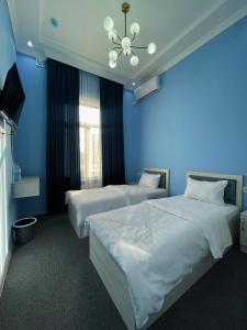 撒马尔罕IMAM AZAM HOTEL的蓝色墙壁客房的两张床