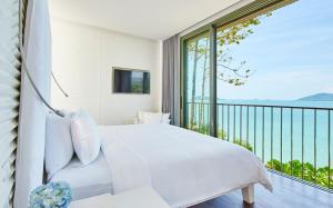 班巴克洛COMO Point Yamu, Phuket- SHA Extra Plus的一间带白色床的卧室和一个阳台