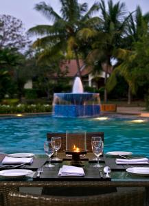 海得拉巴The Golkonda Resort and Spa的一张桌子,上面有酒杯,一张蜡烛在游泳池边