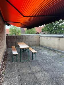 波尔塔韦斯特法利卡Monteurzimmer的一张野餐桌和两把长凳,放在红伞下