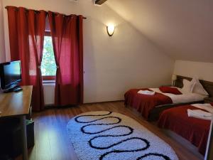 布朗宾客宾馆的一间卧室配有两张带红色窗帘的床和电视。
