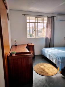 路易港Port Louis Centre penthouse的一间卧室配有一张床、一张桌子和一个窗户。